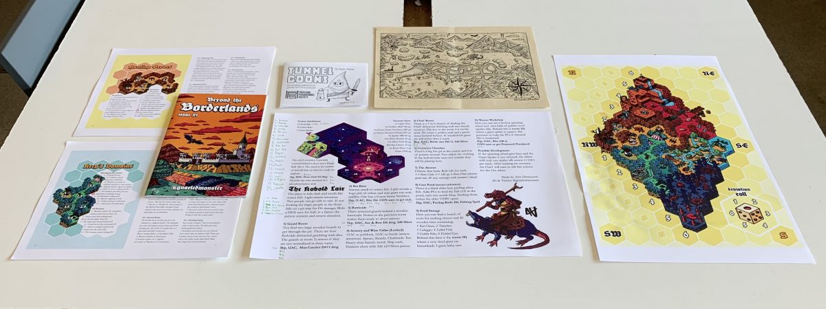 Various zines, maps, and player sheets layed out on table