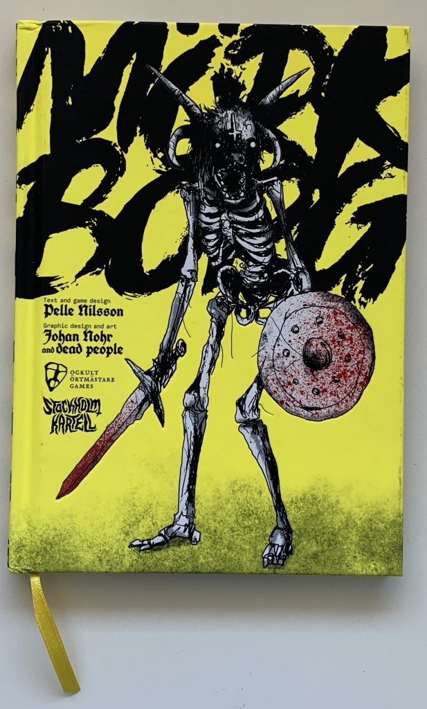 Gamebook cover: Mörk Borg by Pelle Nilsson and Johan Nohr. A horned skeleton with bloody sword and shield on a bright yellow background with agreesive black brush painted text breaking of the book cover's edge.
